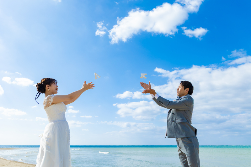 イニシャルの小物を空に投げて青空も使ったフォト◎