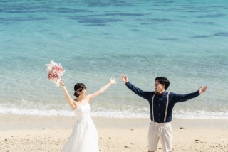 見つめ合いながら、両手をあげる姿。ビーチの青に、おふたりの姿が映える1枚。ピンク色のブーケも可愛らしく、ワンポイントになっています。楽しげな雰囲気が伝わってくるような写真も、大切な思い出になりますよ。