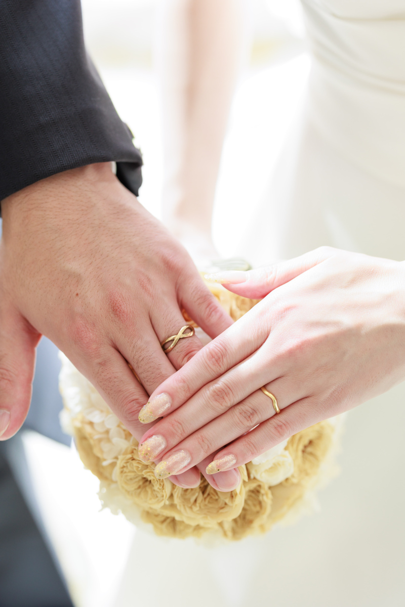 重なり合う手と手、ふたりの結婚指輪が輝いています