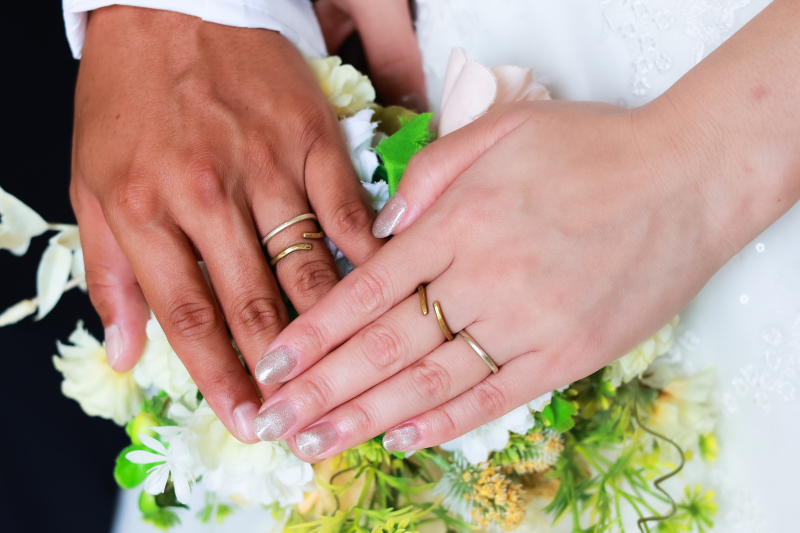 重なり合う手と手、ふたりの結婚指輪が輝いています