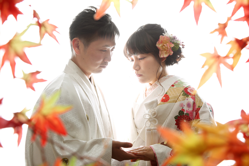 紅葉に囲まれて手を取り合うふたり。