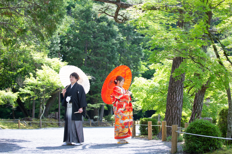 番傘を持って新緑をバックに