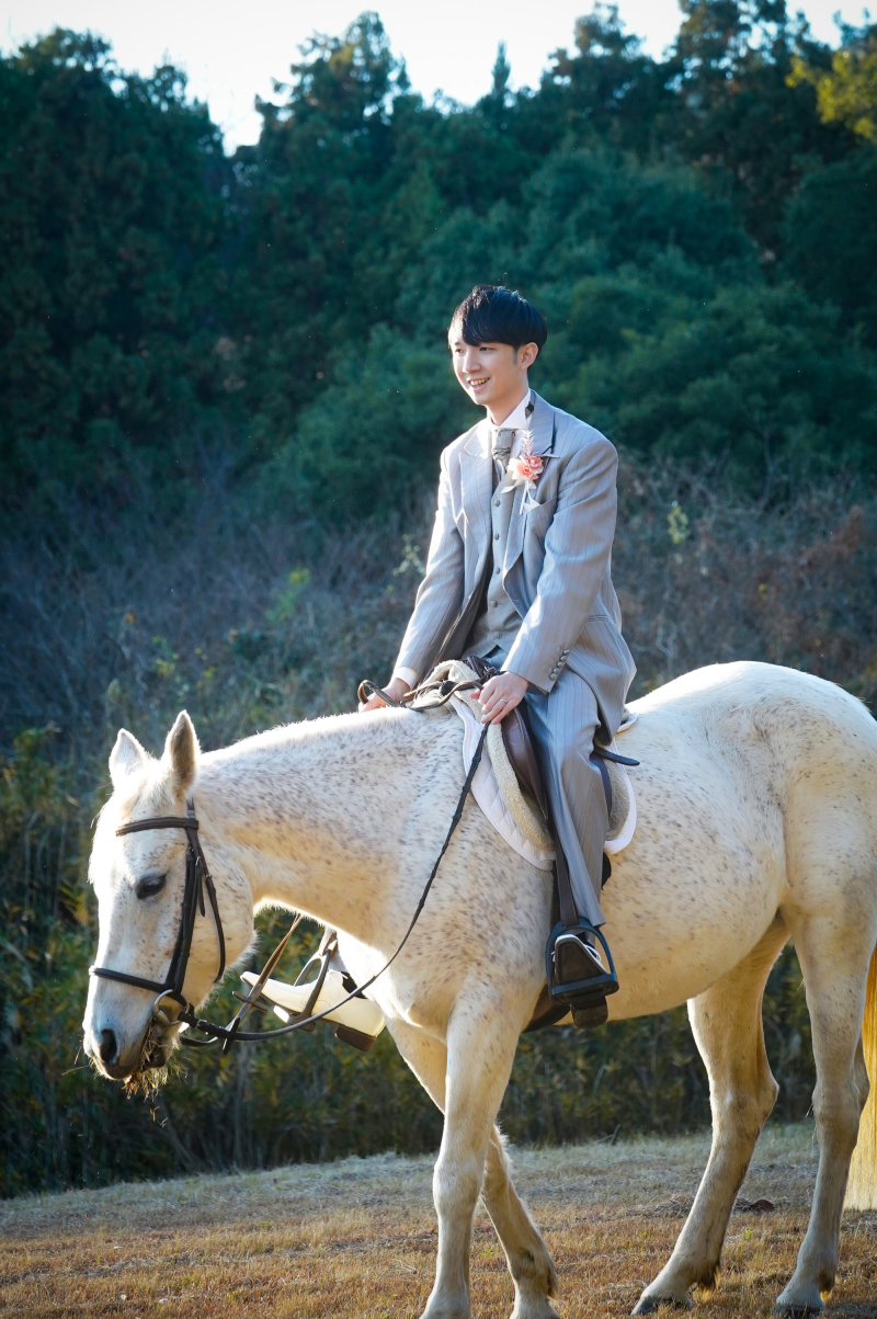 スタイリッシュなタキシード姿で白馬を乗りこなして