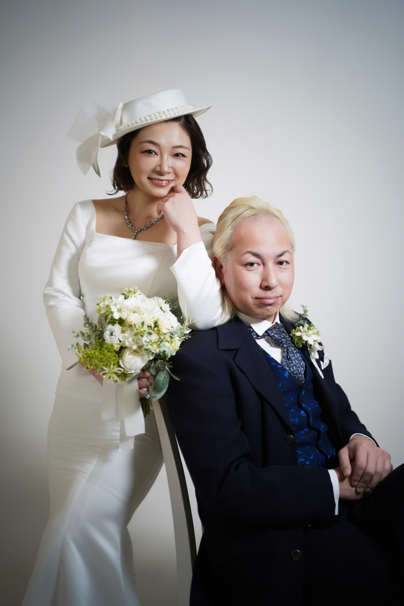 椅子に腰掛けた新郎様と微笑む新婦様