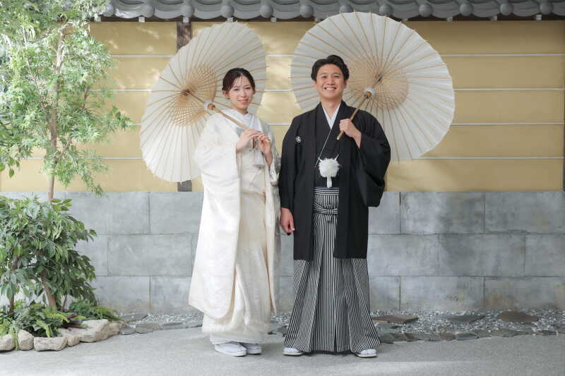 白い和傘を手に、柔らかな笑顔で見つめ合う二人