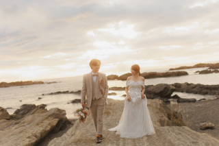 曇天の海辺に、ふと雲が切れて夕日が差し込んだ奇跡のような瞬間。柔らかな光がふたりの歩みに重なり、景色も空気も一度にやさしく色づいた。その一瞬を逃さず、そっと写しとりました。