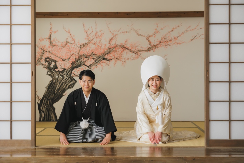 綿帽子をかぶり、畳の上で丁寧なご挨拶