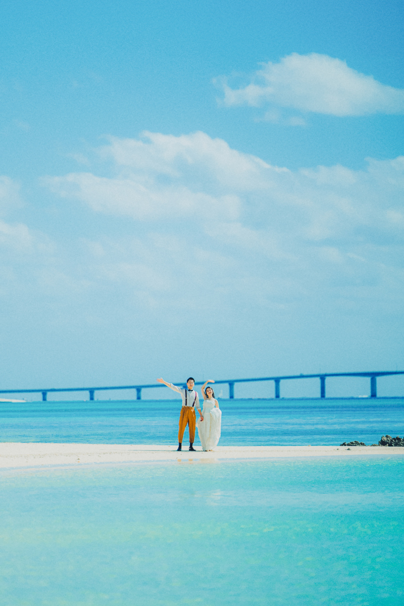 どこまでも続く水平線の中に立つふたりの姿を遠くから。青い空と海、白い雲と砂浜、ずっと記憶に残る美しい景色と一緒に。