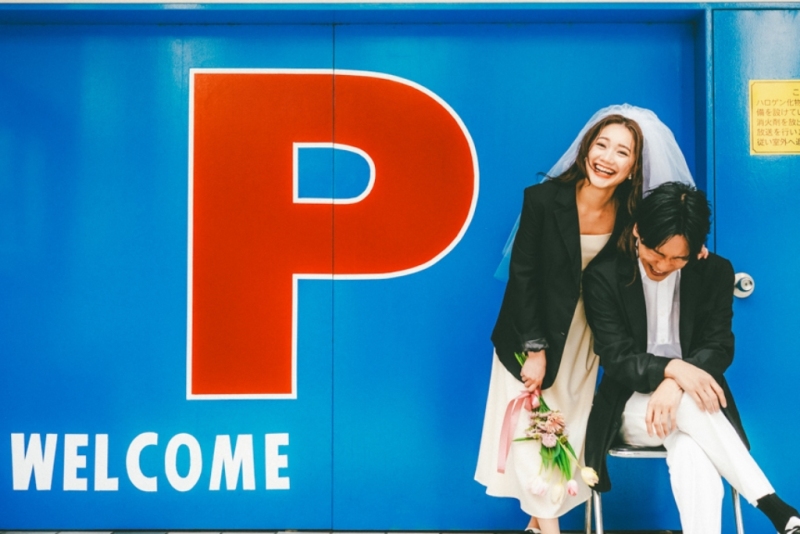 何気ない街角も、二人にかかれば特別な舞台に。弾けるような笑顔と、靴を直すそのやさしい仕草に、飾らない二人らしさが滲み出た一枚です。
