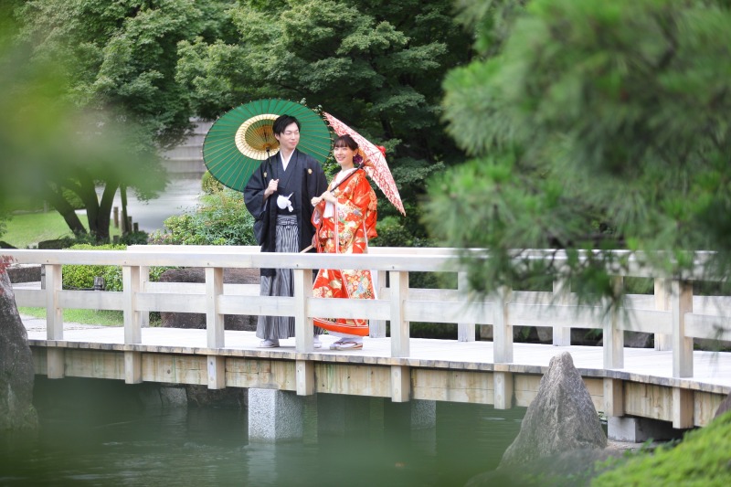 和傘を手に石橋にたたずむ
