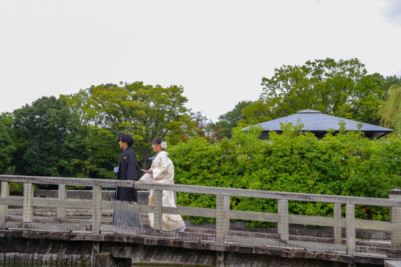 白無垢で歩む庭園の木橋の道のり