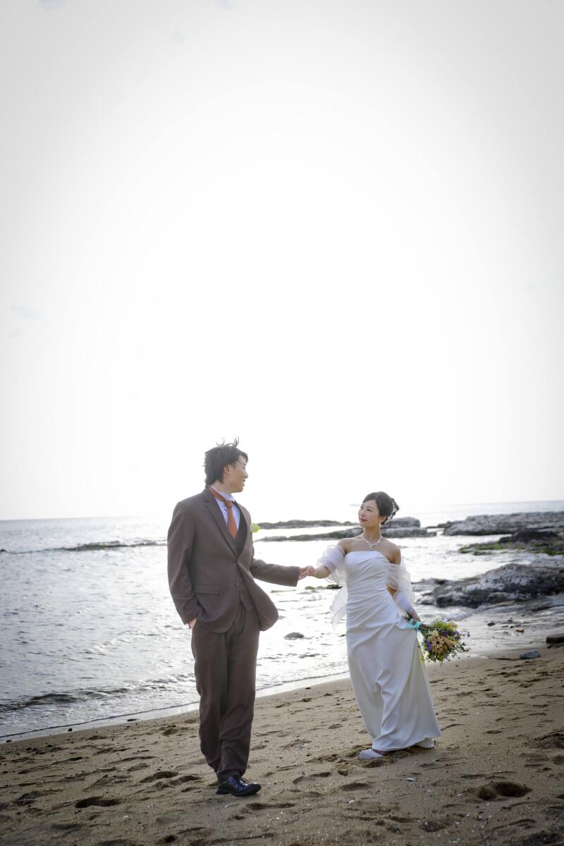 海辺を手を引いて歩くお二人