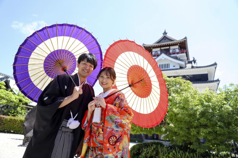 青い空とお城を背に和傘を持って