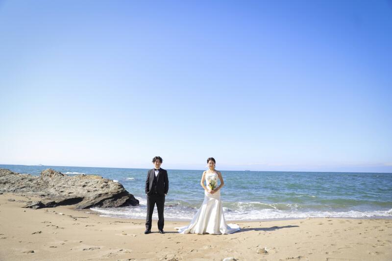海をバックに立つお二人