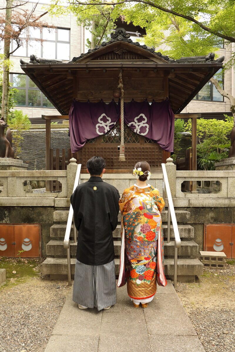 紫の幕がかかる祠に向き合う後ろ姿