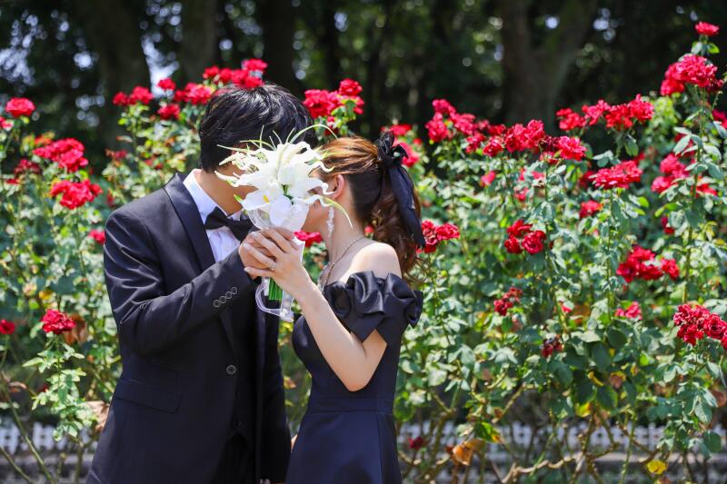 バラ園で花束越しに寄り添う二人