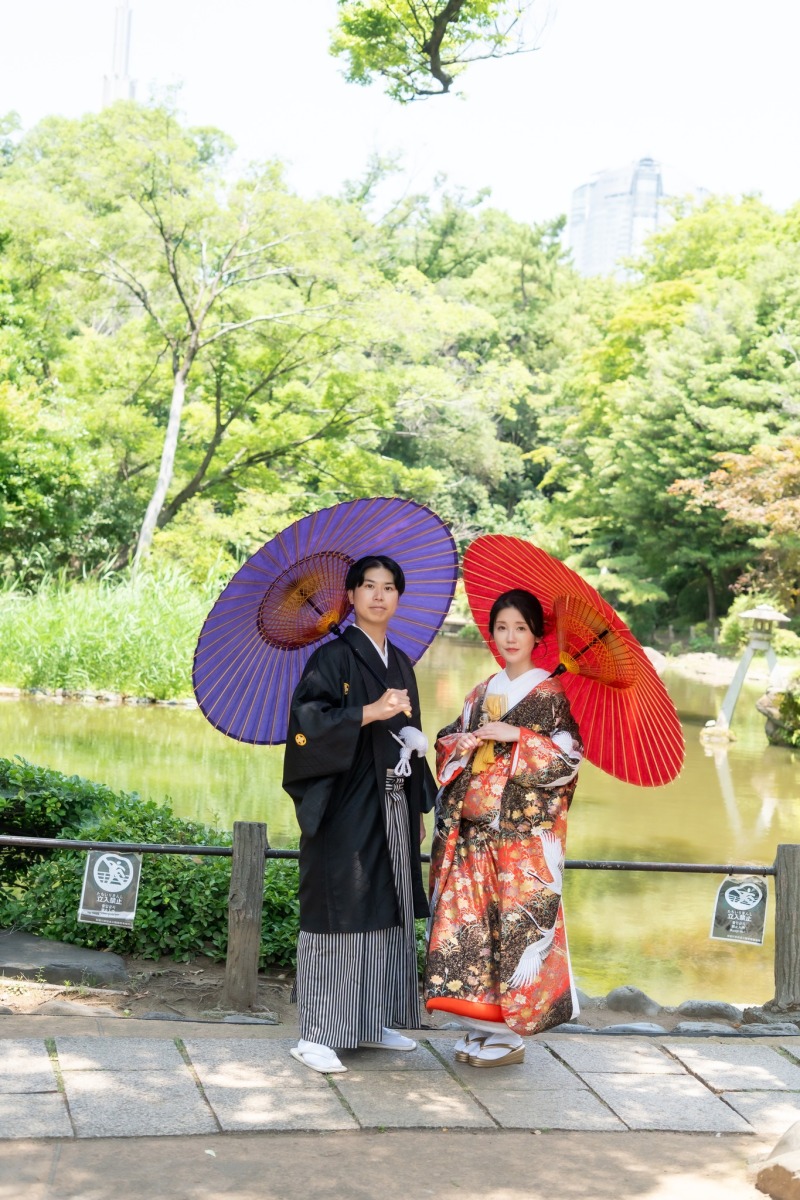 池畔で紫と赤の和傘を手に