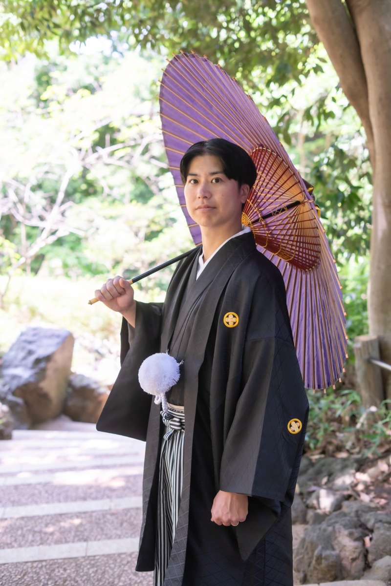 紫の和傘を掲げる新郎