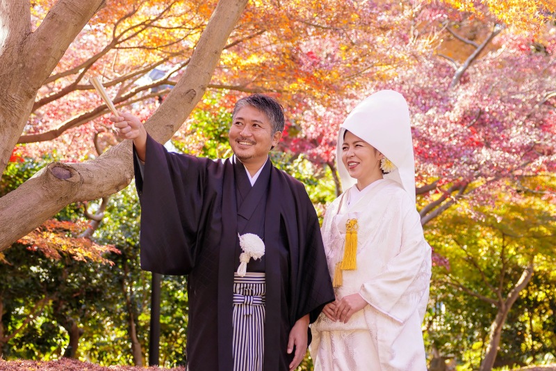 紅葉をバックににこやかな笑顔で