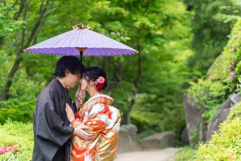 紫の番傘で額を寄せ合う色打掛
