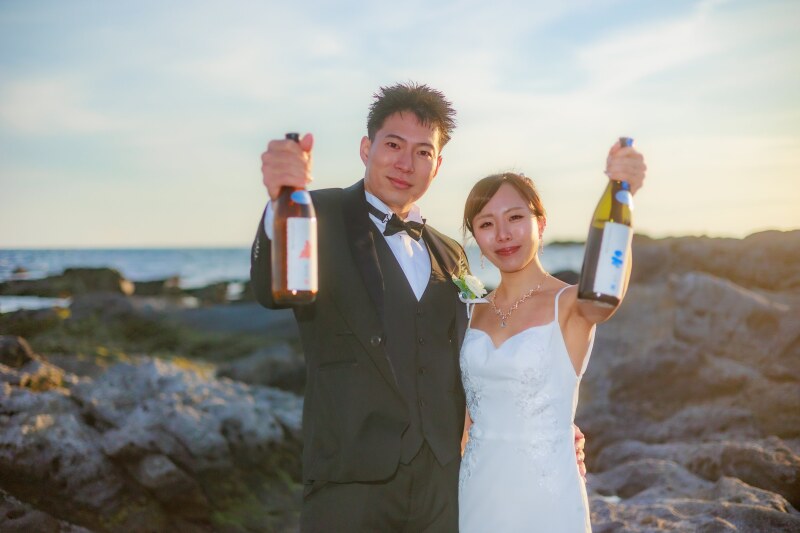 海をバックに乾杯ボトルで祝杯