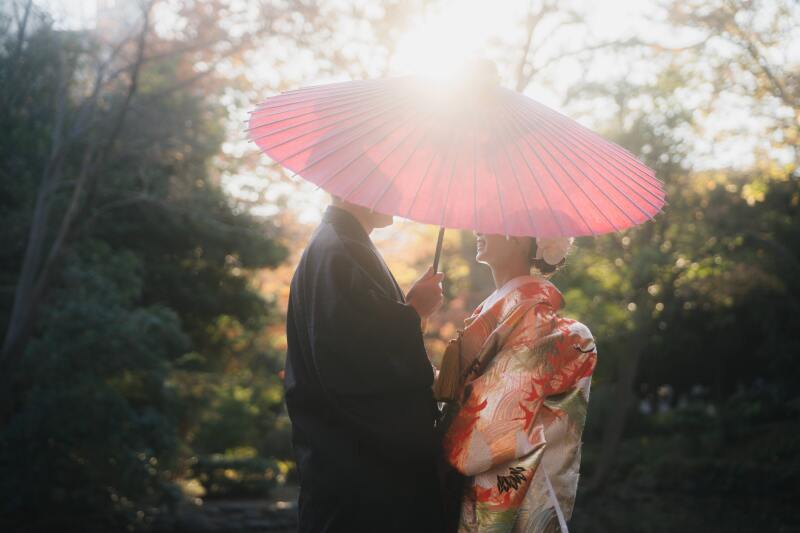 紅葉と和傘に寄り添う二人