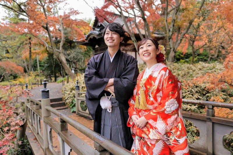 紅葉をバックにニコニコ笑顔で