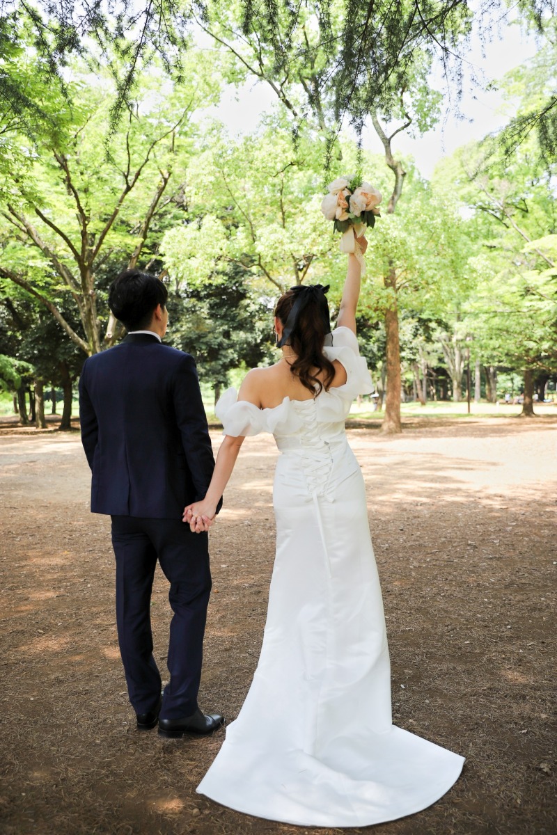 木漏れ日の道で高く掲げたブーケ