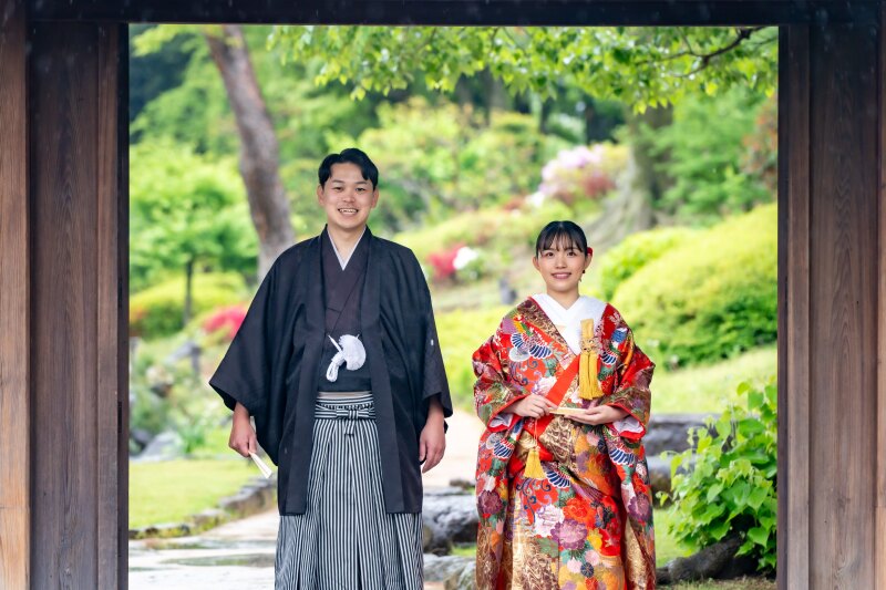 木の門を額縁に、笑顔弾けるお二人