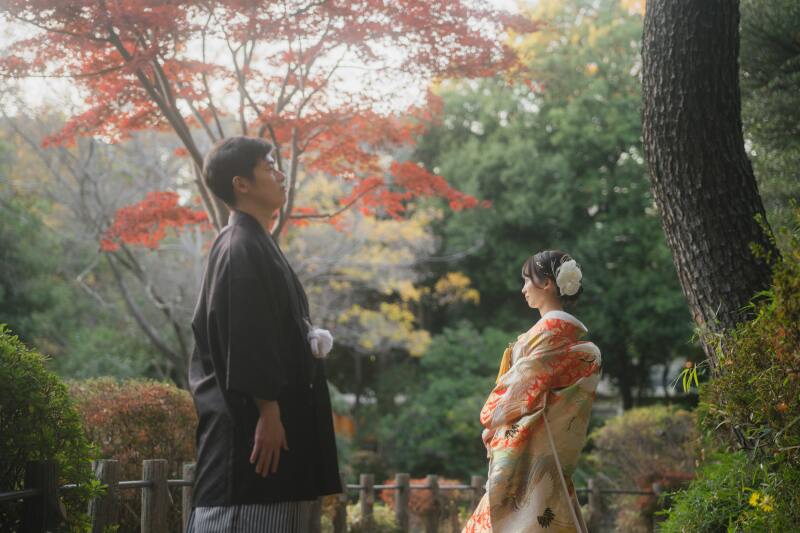 紅葉と松の下でたたずむ二人