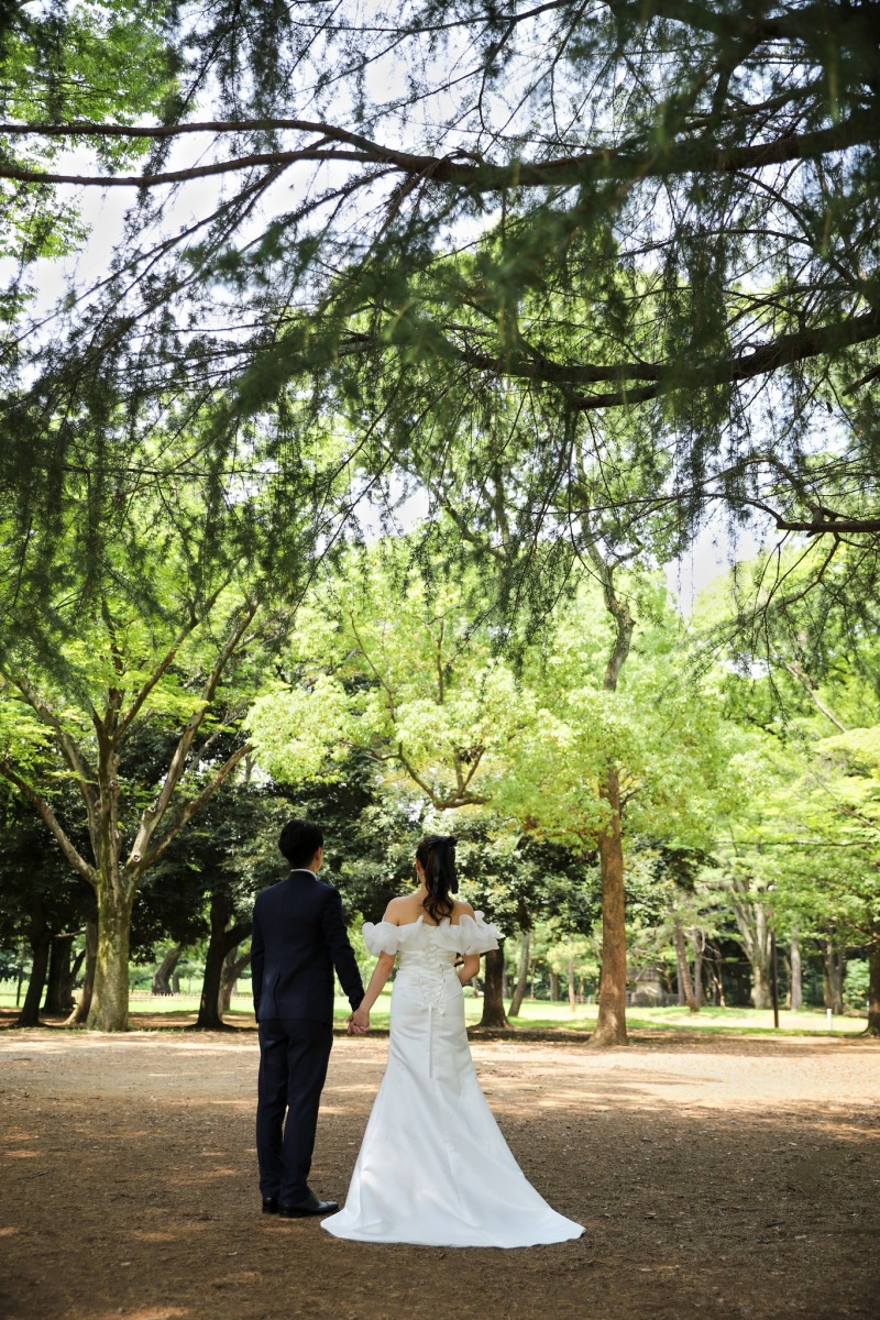 木々の下で手を重ねる後ろ姿とレース