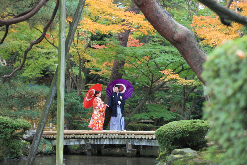 紅葉をバックに番傘を持ちながら