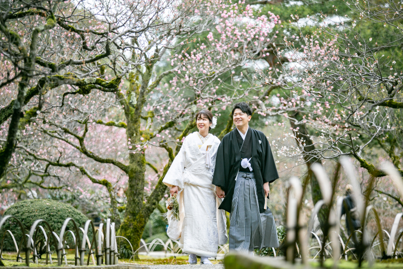 紅白梅を背に笑顔でウォーキング