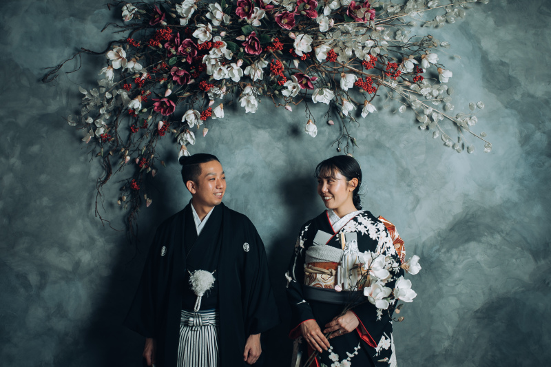 グレージュの壁と紅白の花の下で