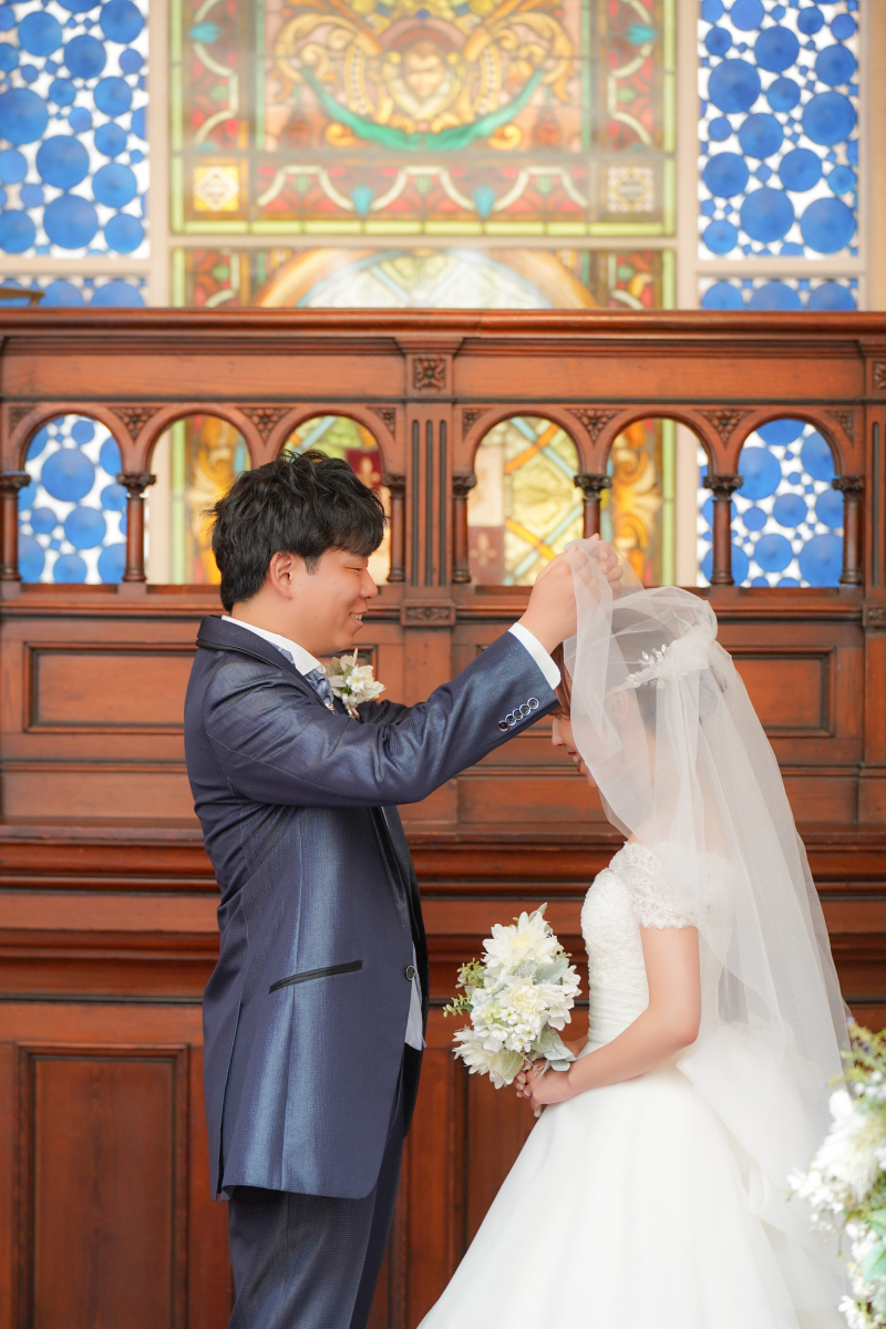 永遠を誓うベールアップ、ステンドグラスの前で。