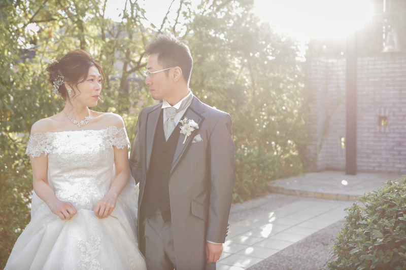 スタジオ外の鐘の前で