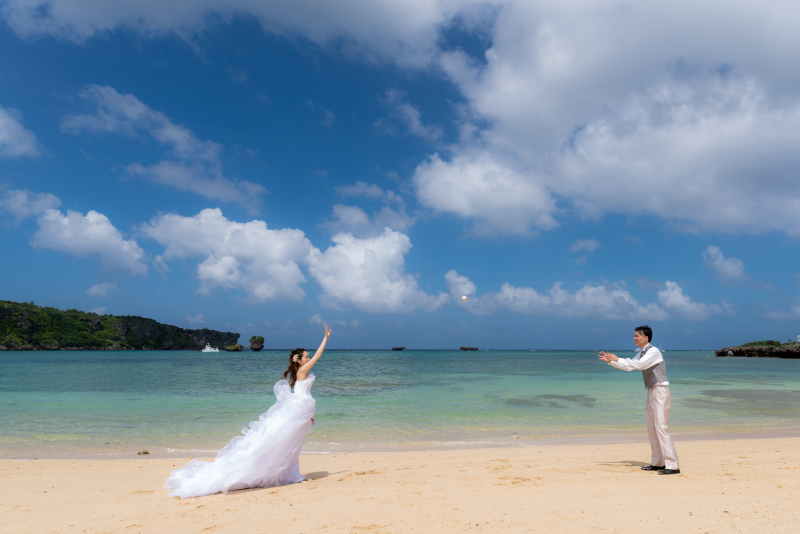 エメラルドグリーンの海と青い空を背景に、ビーチでドレス&タキシードを着て楽しむキャッチボール。非日常感のフォトウエディングの空間で、日頃のおふたりのなかよしさを感じさせる、自然なショットになりました。