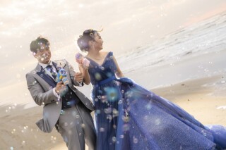 海風を感じながら、シャボン玉に包まれて笑い合うおふたりの姿を捉えた、楽しさあふれるロケーションフォト。夕暮れの柔らかな光が海辺を包み込み、ブルーのドレスが美しく輝きます。