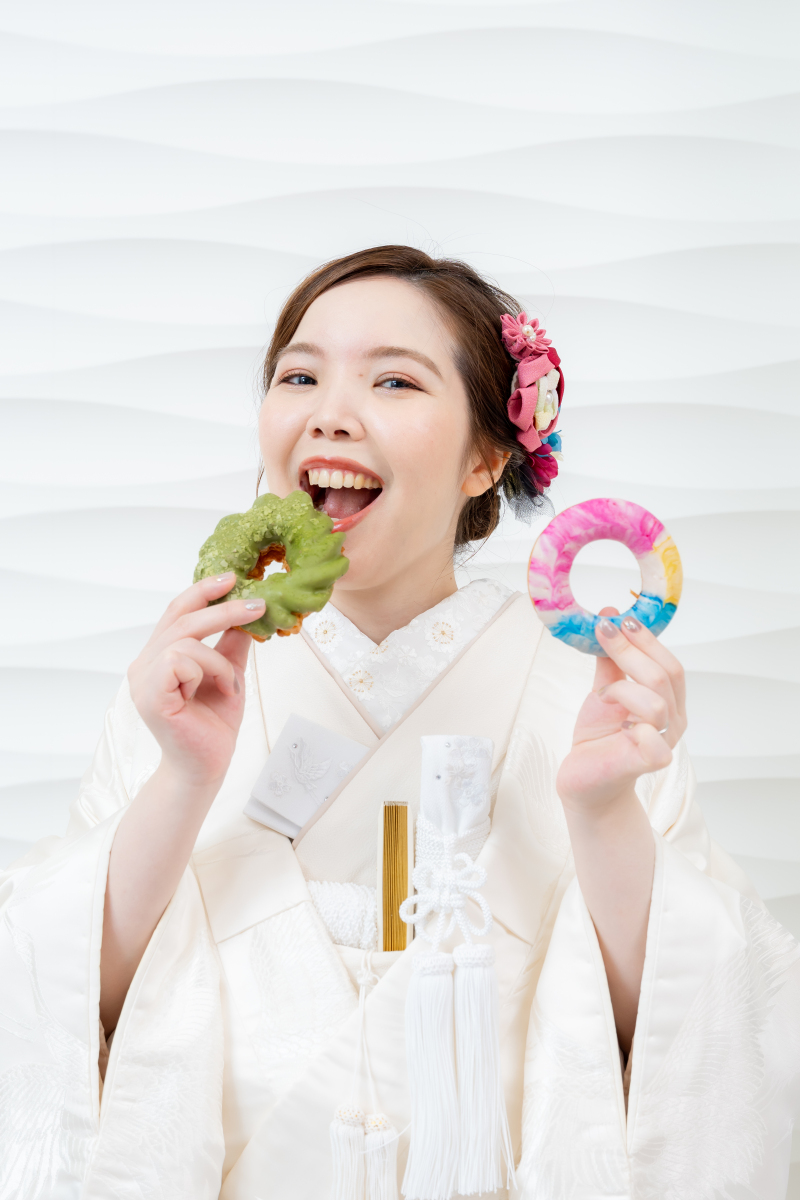 ドーナツを手に持ちお茶目な笑顔を見せる新婦様です