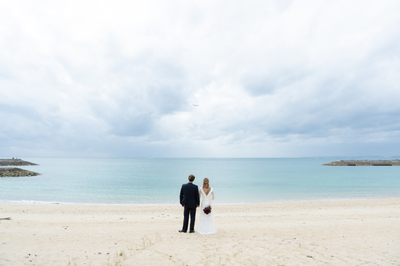 静かな沖縄の海を背に未来を見つめるふたりの後ろ姿