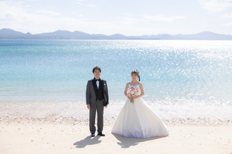 青くきらめく沖縄ブルーの海と並ぶ晴れやかな立姿