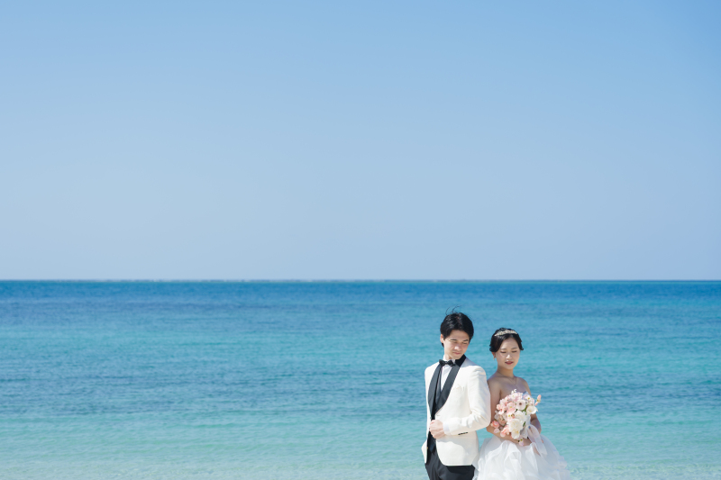 背中合わせに伝わる絆。透き通る海を背景に佇む姿。