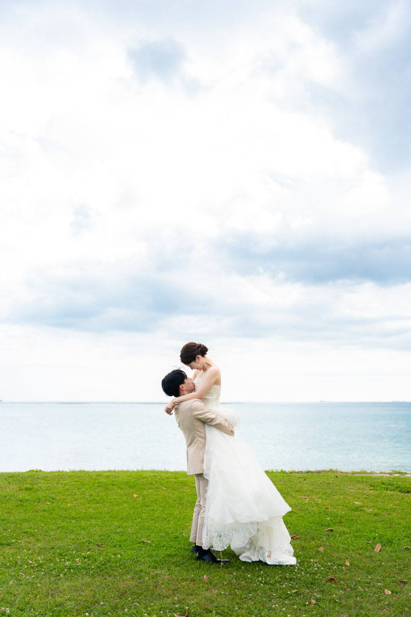 海が見える岡で空へ向かって新婦様を愛おしくだっこ