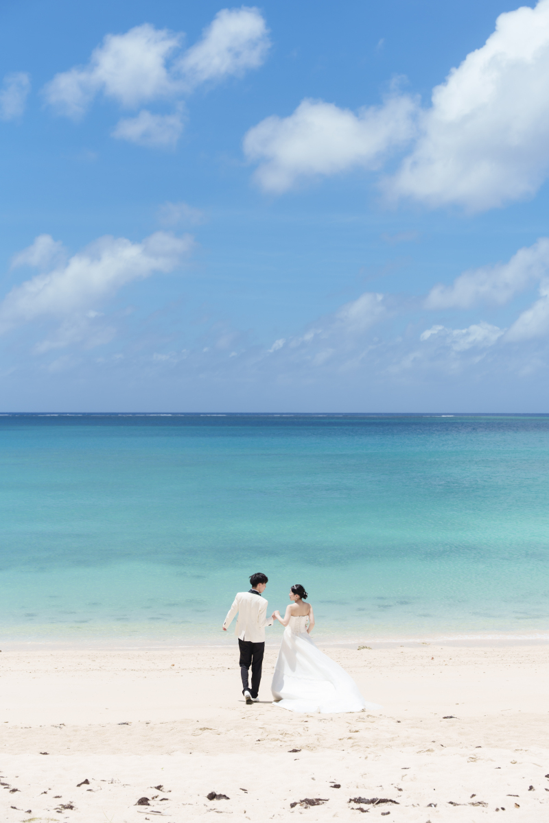 青空と海に包まれるながら時を刻むふたりと記念写真