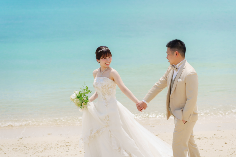 綺麗な海を背景に、手を繋いでビーチをお散歩