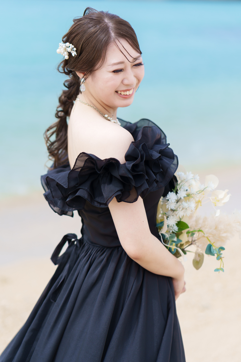 振り返り微笑む花嫁。波打ち際に映える黒ドレス