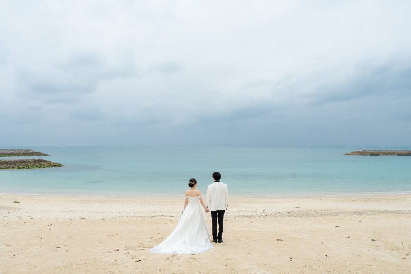 沖縄の青い海を背に、未来へと歩むおふたりの後ろ姿