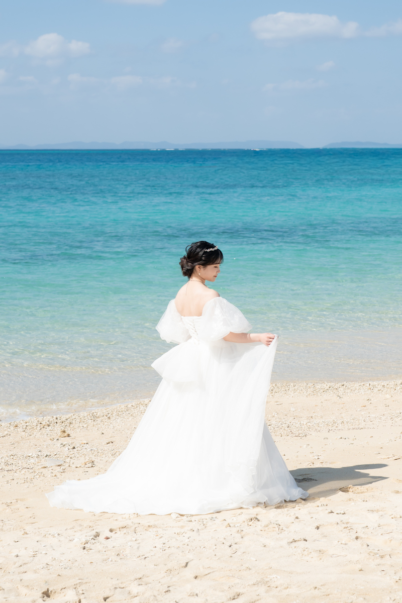 風にひらひらと揺れるドレスと青い海の光のきらめき