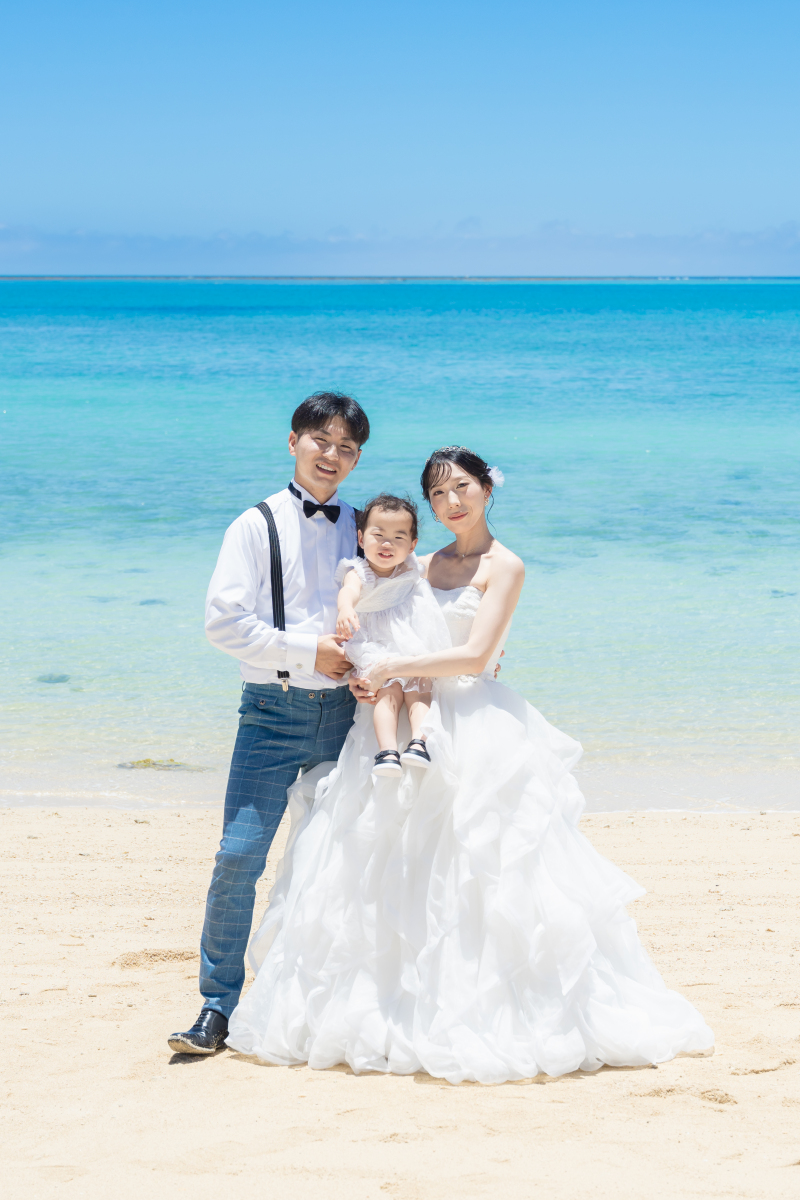 真っ白なドレスを着たお子様と一緒に家族で記念撮影