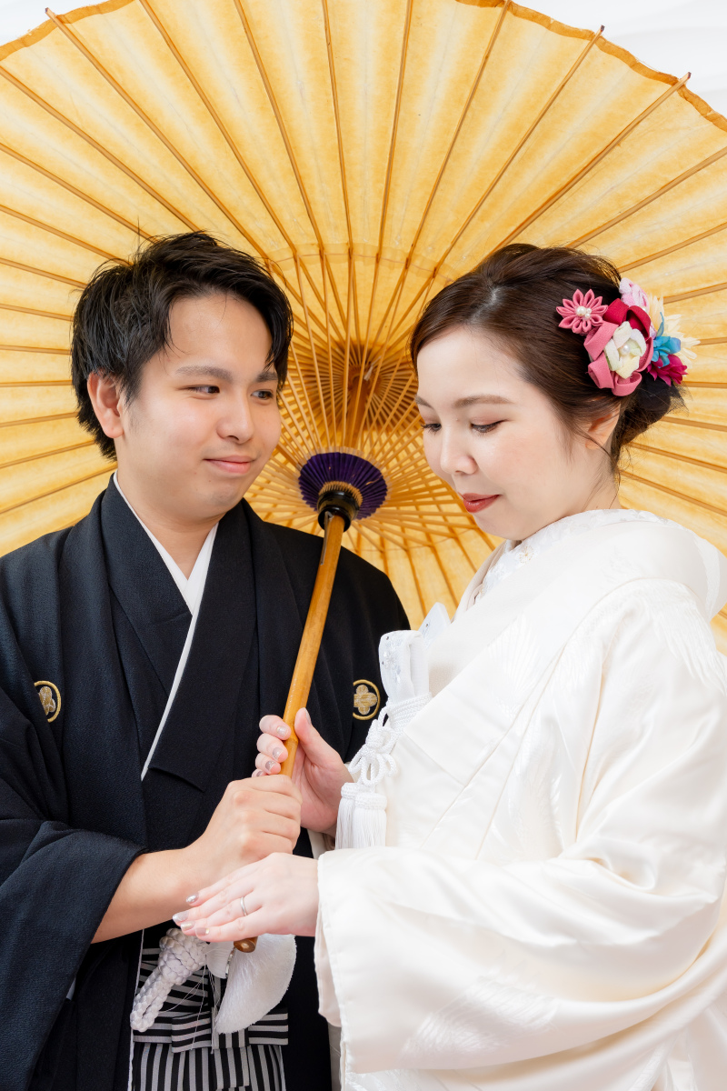 和傘の下で寄り添いながら手元を見つめる美しい1枚